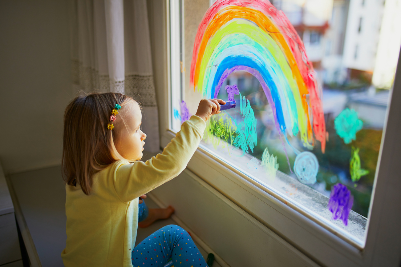 Toddler Drawing Rainbow on Window Glass